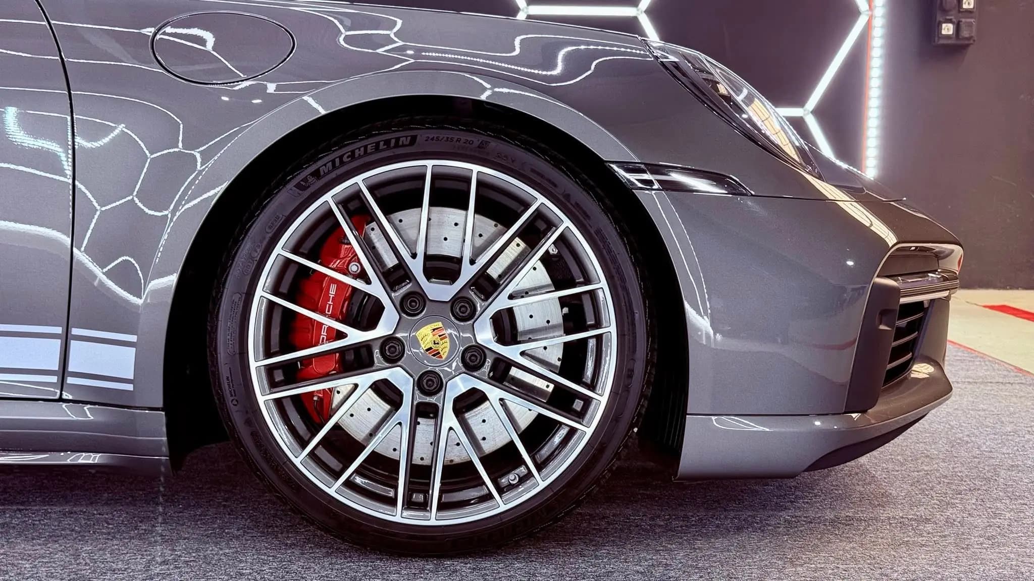 Porsche 911 első kereke és féktárcsája közelről, tükörfényes lakkal